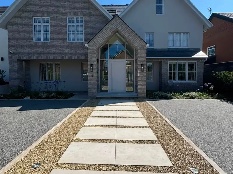 Grey resin bound driveway with porcelain path to a modern detached house