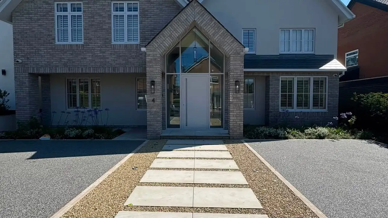 Grey resin bound driveway either side of a porcelain stepping stone path to a modern detached house